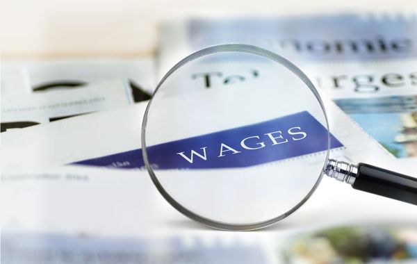 Magnifying glass highlighting the word 'wages' to indicate payroll services