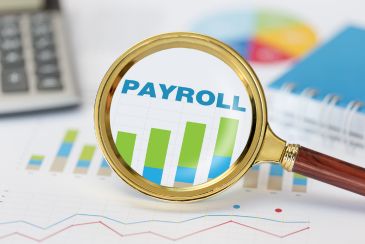 Cover photo for The Gardner Webb Guide to Outsourcing Payroll Services - A magnifying glass is increasing the size of the word payroll and a chart on a piece of paper